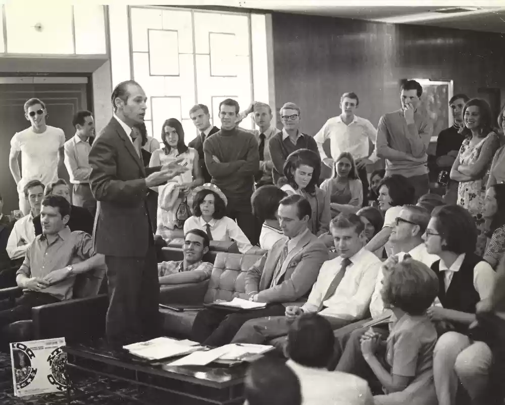 Robin Jones encourages Ambassador UK Talent Show team – emcee Neil seated center next to mentor Peter Butler (looking at camera)